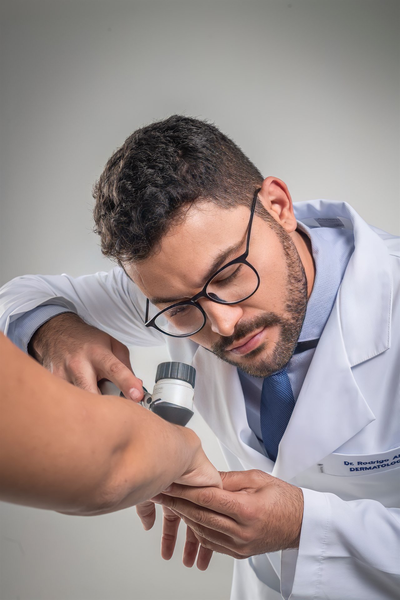 Dr. Rodrigo Alves realizando exame dermatológico com dermatoscópio